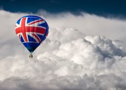 A hot air Balloon with a Union flag motif flying in front of dramatic storm clouds