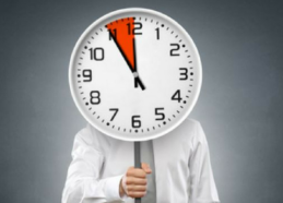 Business man face hiding behind a clock