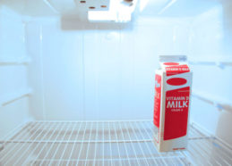 Solitary carton of milk in a white fridge