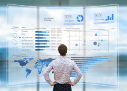 Businessman analyzing a business analytics (BA) or intelligence (BI) dashboard on virtual screen showing sales and operations data statistics charts and key performance indicators (KPI)